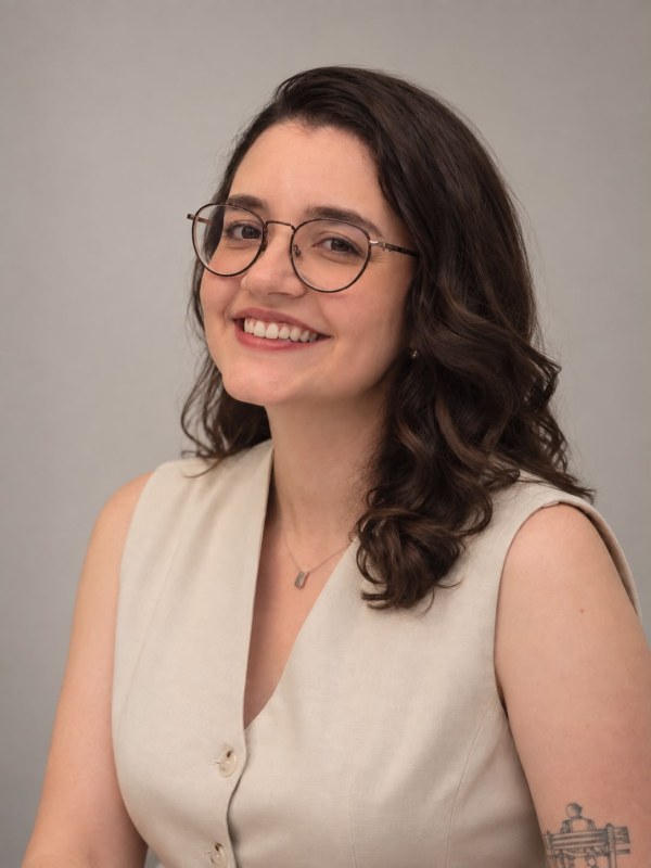 Gabriella Ramos sorrindo, de óculos e colete claro
